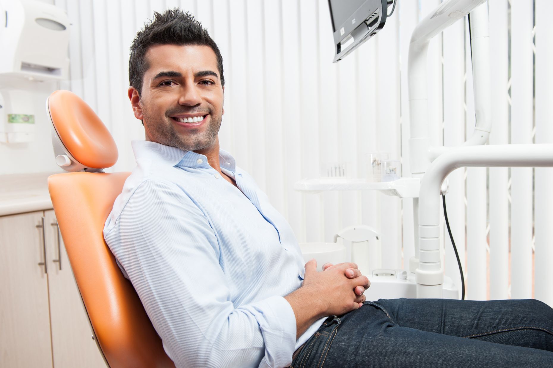 A man with beautiful smile sitting in a dental chair after restorative cosmetic dental treatment