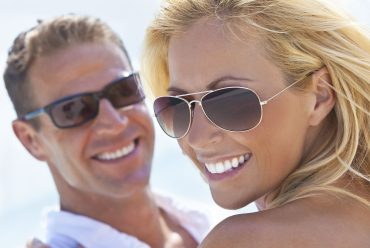 Happy attractive woman and man with perfect smiles walking on a beach.